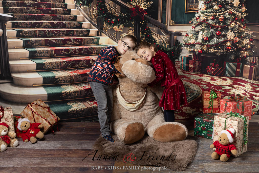 Weihnachts-Shooting mit Kindern vor weihnachtlich geschmückter Treppe mit großem Bär